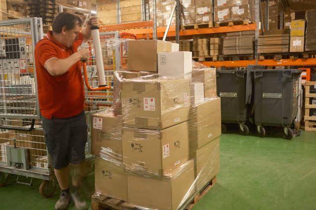 Une personne de l'équipe emballe des cartons sur une palette.