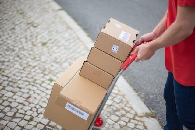 A delivery person transports packages on a trolley.
