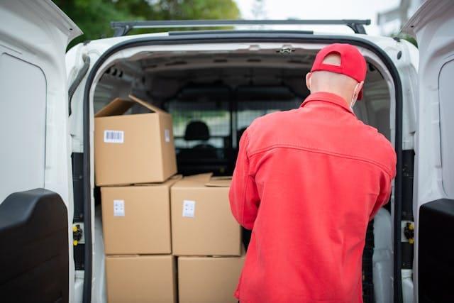 A driver takes a box from his delivery van.