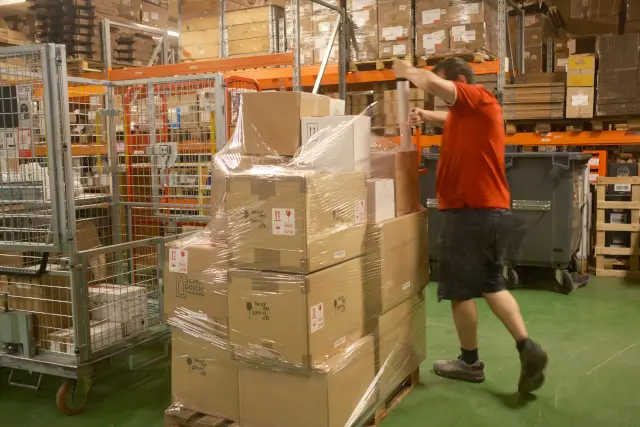 Un employé emballe des cartons sur une palette.