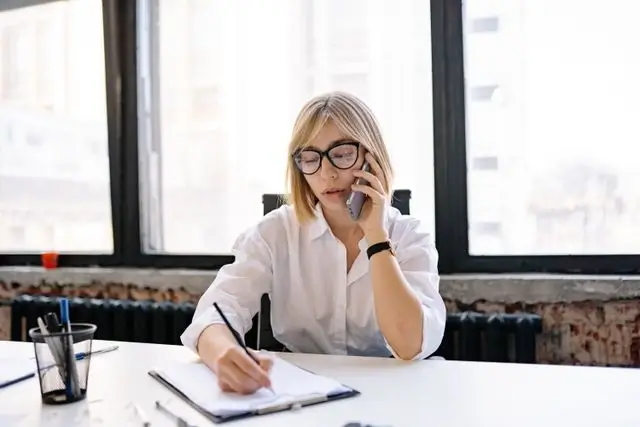 A secretary on the phone takes notes.