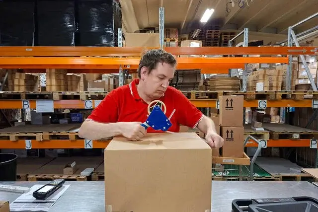 Un employé emballe des cartons.