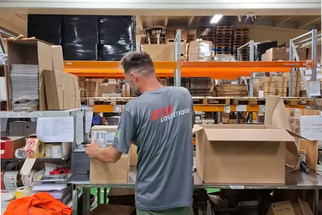 Un employé colle des étiquettes sur des cartons.